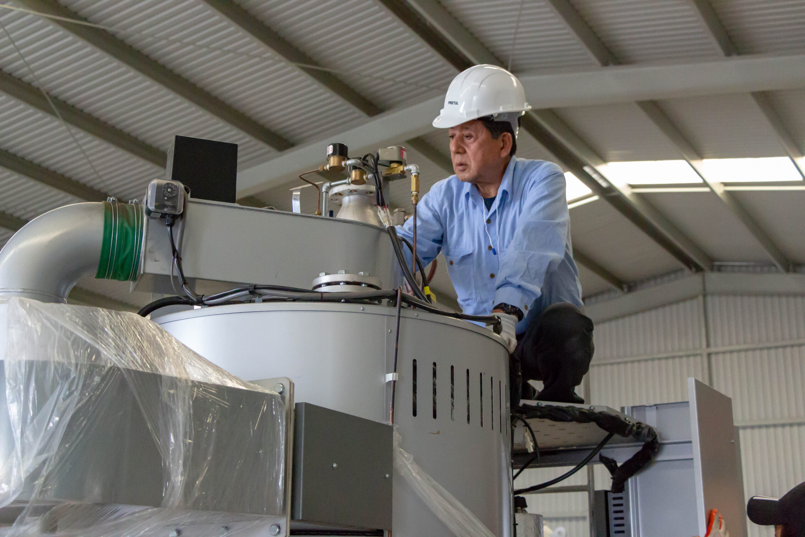 Engineer working on industrial machinery while wearing a safety helmet